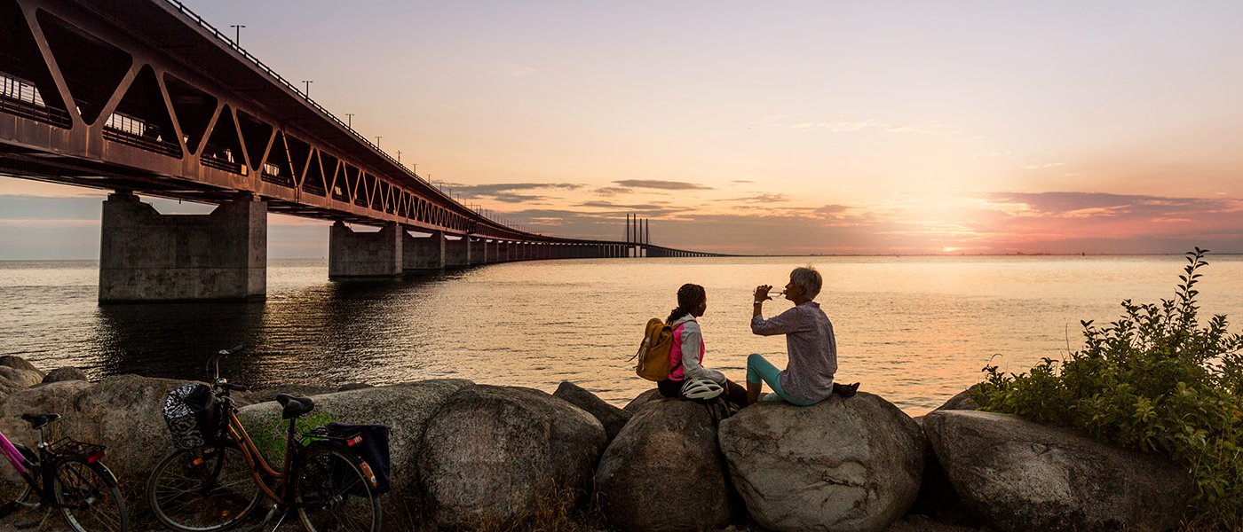 Two persons sitting by the Oresund bridge in Malmö 