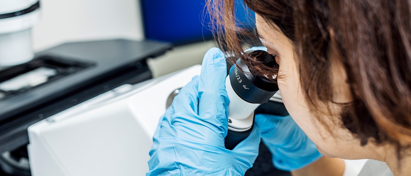 Woman looks through a microscope