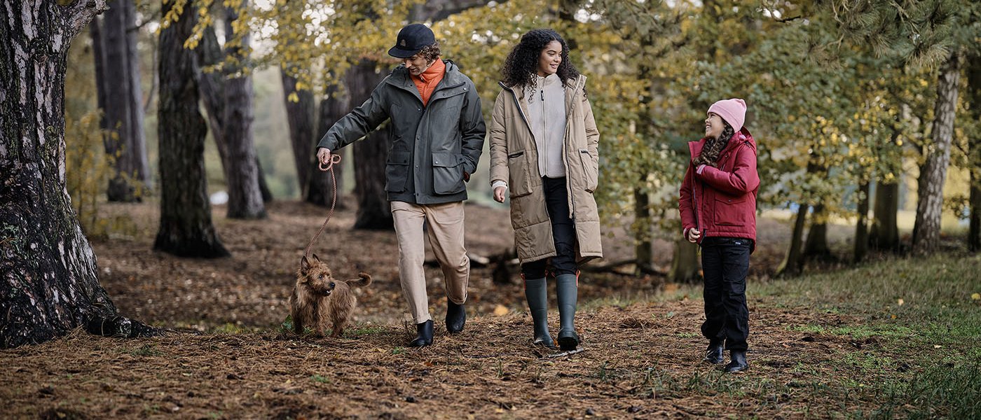 A family are walking in the forest with their dog