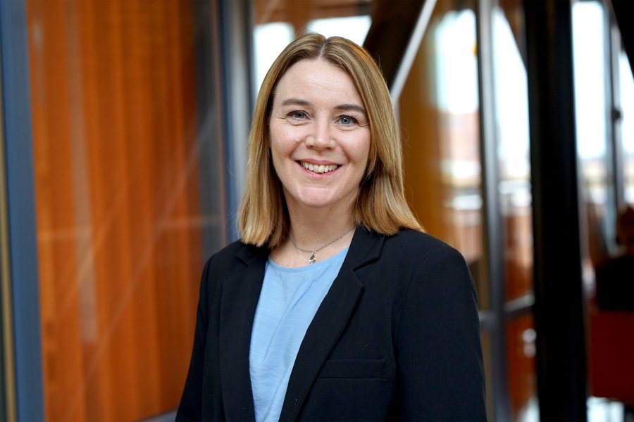 Portsätt av en kvinna som ler in i kameran. Hon bär en blå tröja med kavaj över.