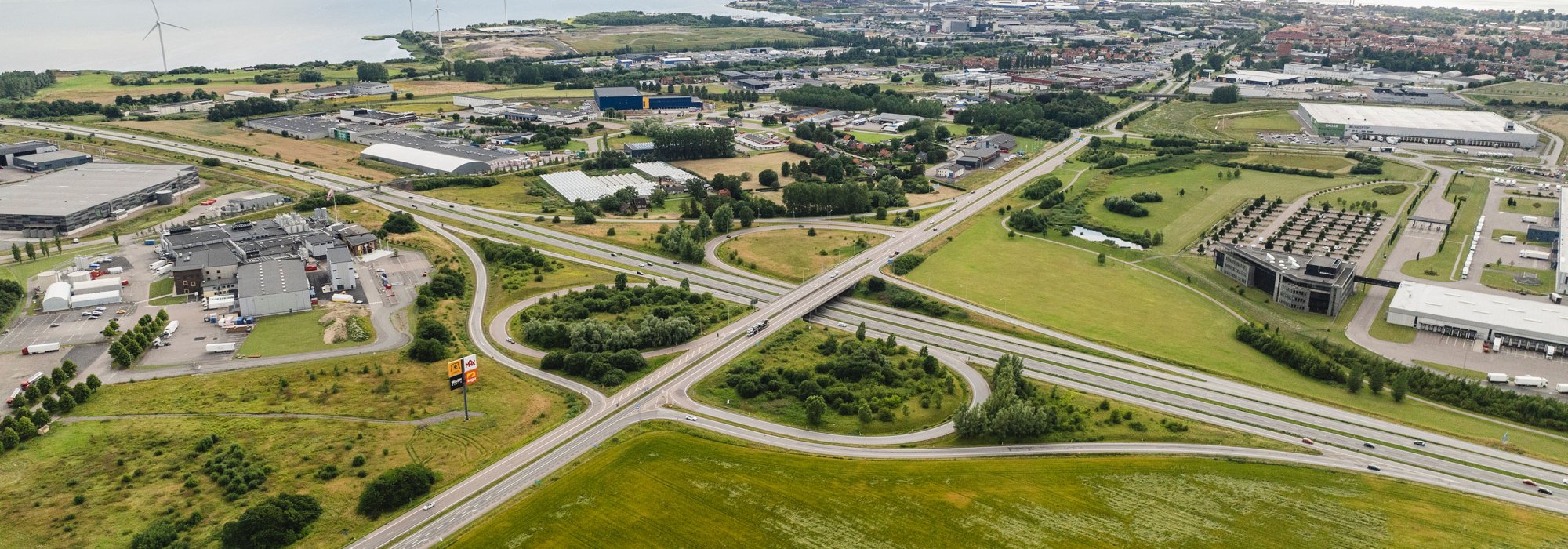 Drone image over a landscape. Green field, city and ocean. Daytime.