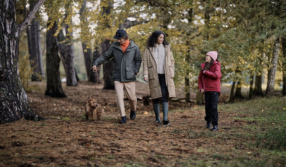 A family are walking in the forest with their dog