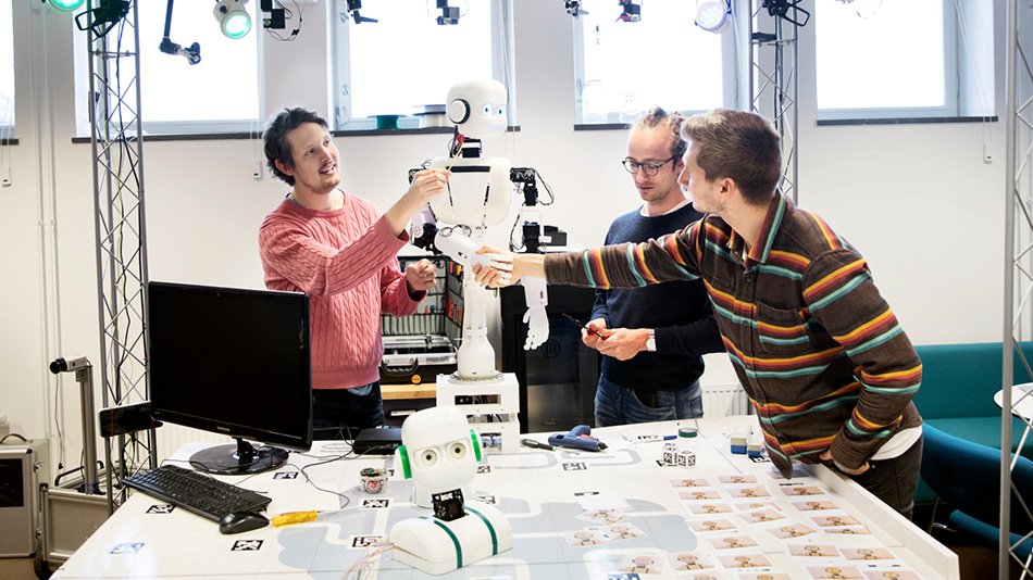 Three men working with a robot