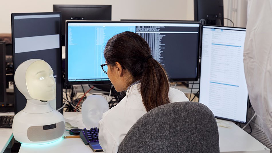 Woman sitting by a desk developing robot