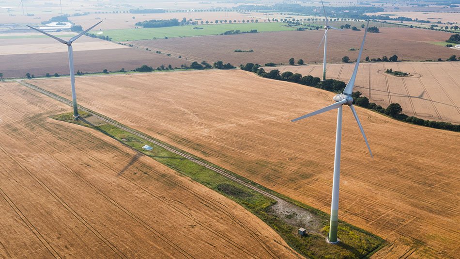 A drone image of two wind turbines in an open field