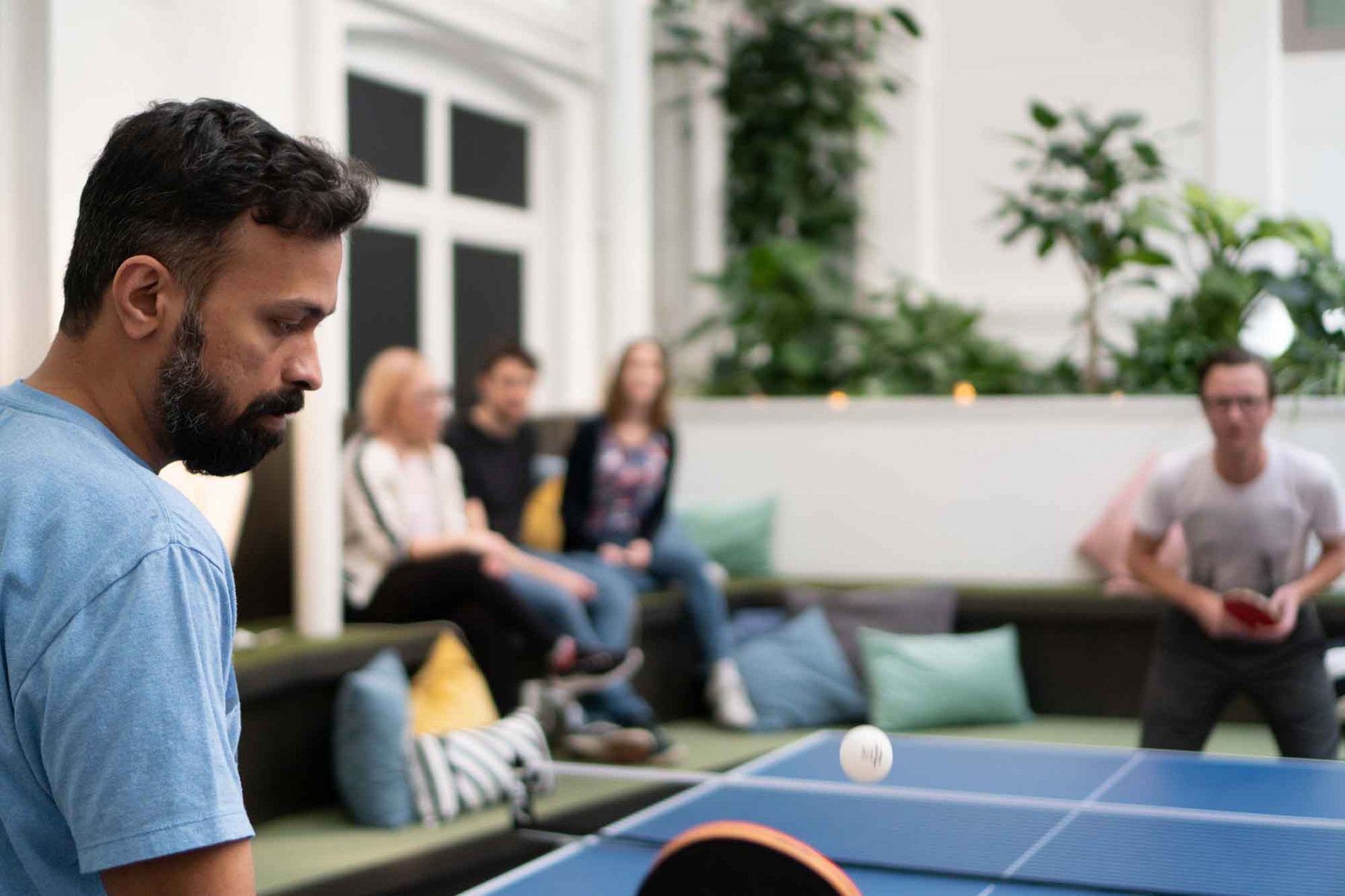 A man playing ping pong with colleagues