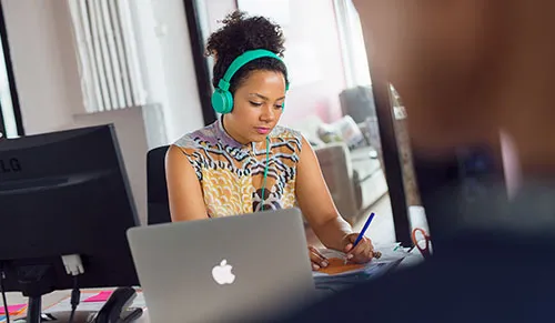 Woman listening to music while writing