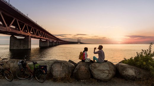Two persons looking at the sunset by the Öresund bridge